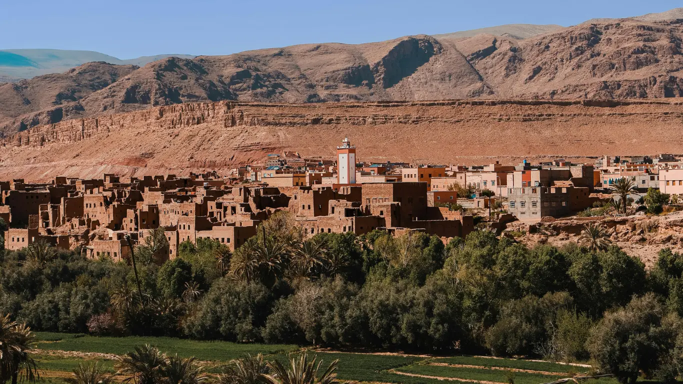 Traditional Berber village with earthen houses and mosque nestled at the foot of the Atlas Mountains on a 3-day Marrakech to Merzouga tour.
