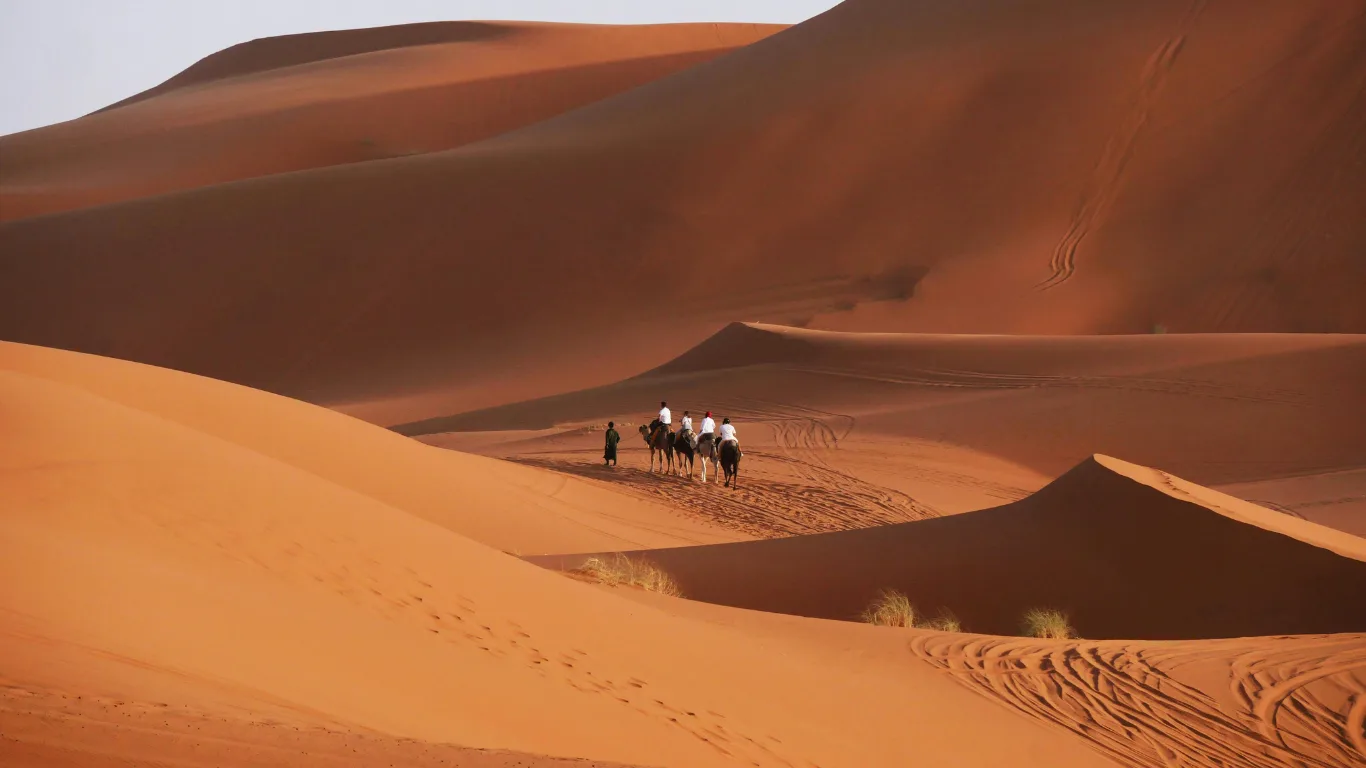 Camel caravan crossing the golden dunes during a Fes to Marrakech desert tour 3 days experience.