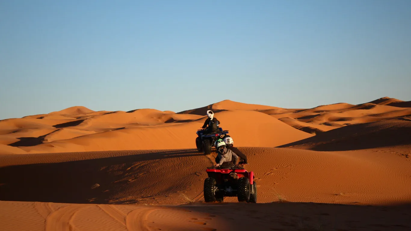 Travelers riding quad bikes across the sand dunes during a 3-day Marrakech to Fes desert tour.