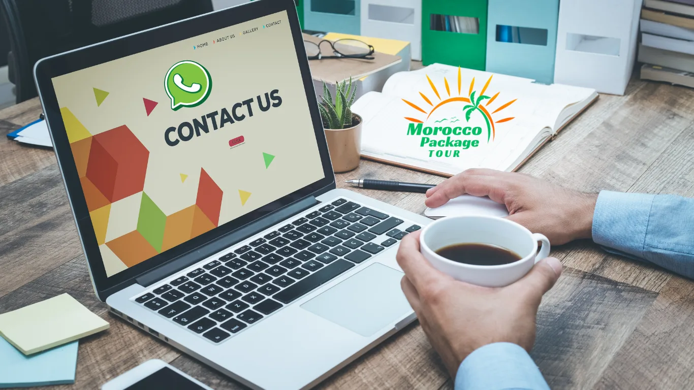 Laptop screen displaying a "Contact Us" page with a WhatsApp icon, next to a coffee cup and Morocco Package Tour logo on a desk.