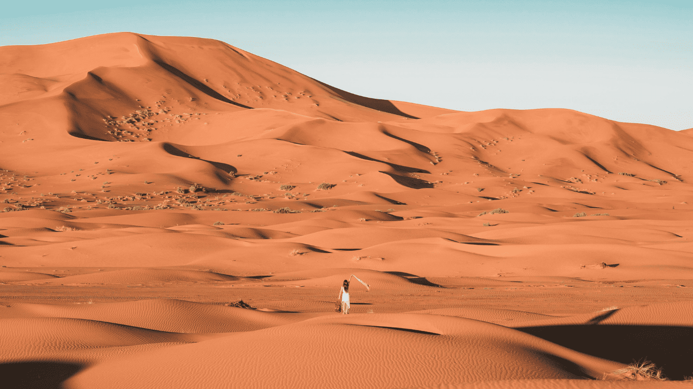 Woman walking through vast sand dunes in the Sahara Desert during a 5 days desert tour from Marrakech