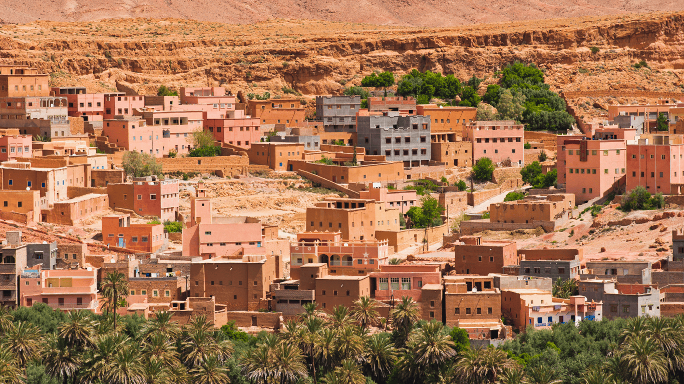 Traditional Berber village with terracotta houses nestled in a desert valley with lush palm trees in southern Morocco.