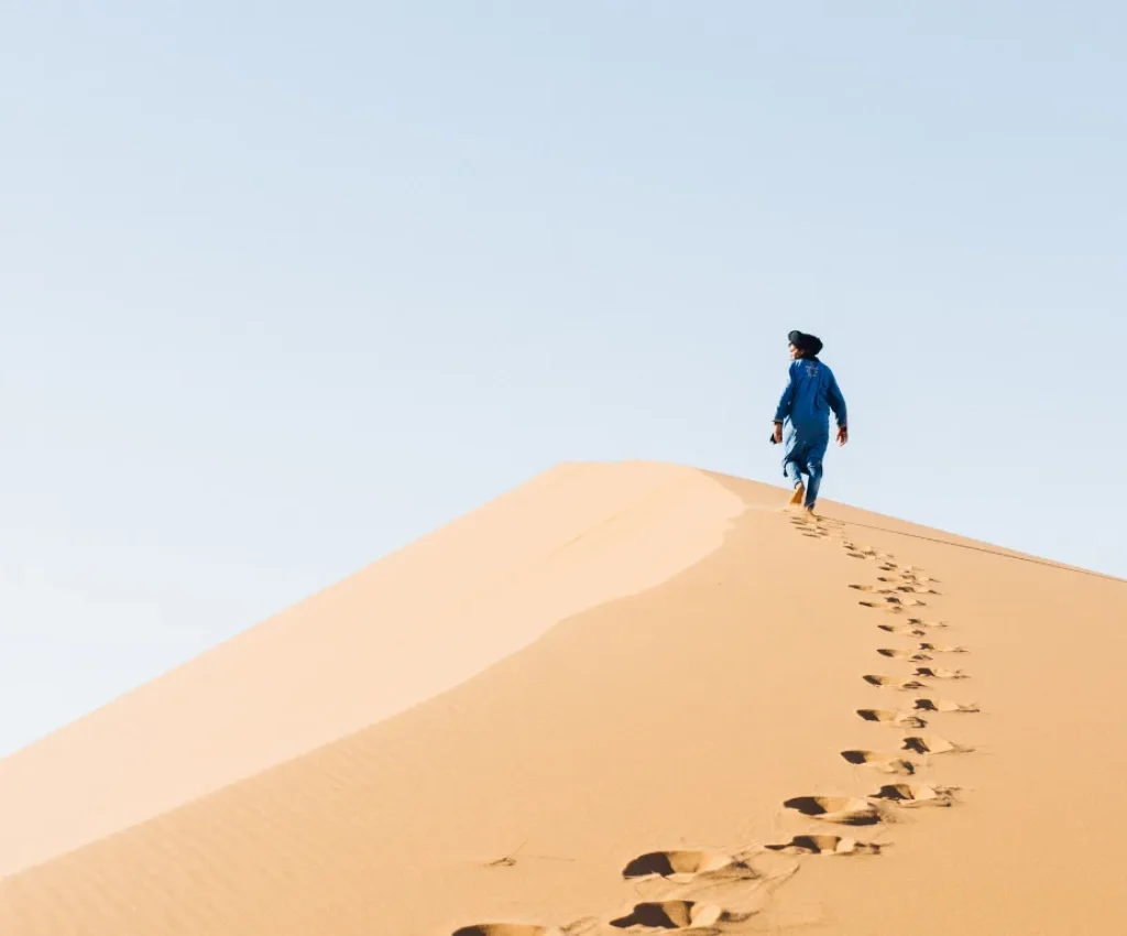 Sahara Desert Experience on a 5 Day Morocco Itinerary Man walking on sand dunes in the Sahara Desert during a 5 day Morocco itinerary