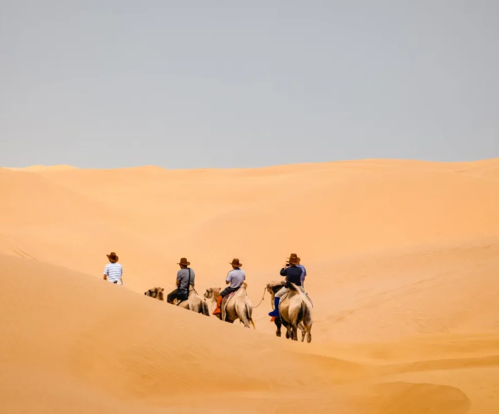 Camel Trekking Adventure – 5 Days in Morocco Itinerary Tourists on camelback trekking across sand dunes on a 5 days in Morocco itinerary