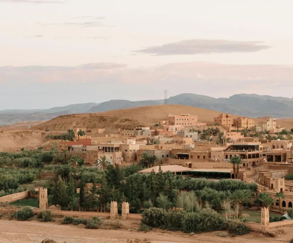 Morocco Tours 4 Days – Discover Hidden Villages and Oasis Landscapes Panoramic view of a traditional Moroccan village surrounded by palm groves during Morocco tours 4 days.